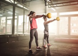 Two woman lifting kettle bell in cross fit gym