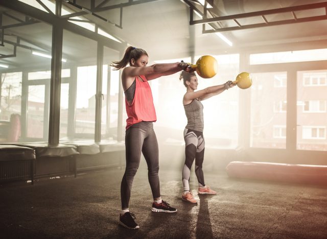 Two woman lifting kettle bell in cross fit gym