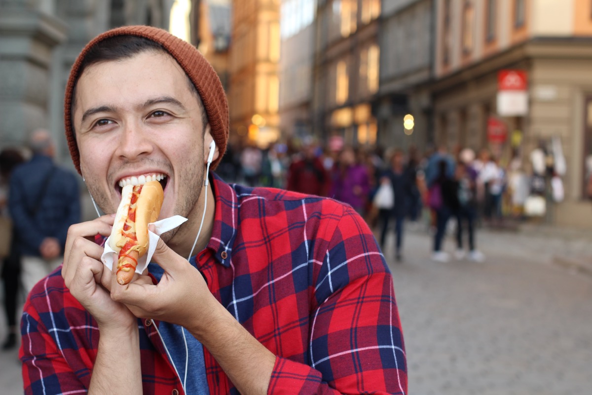 man eating hot dog on city street