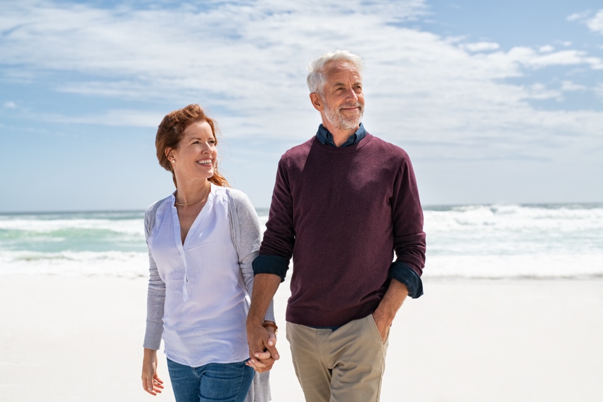 Senior couple walking on beach.