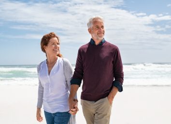 Senior couple walking on beach.