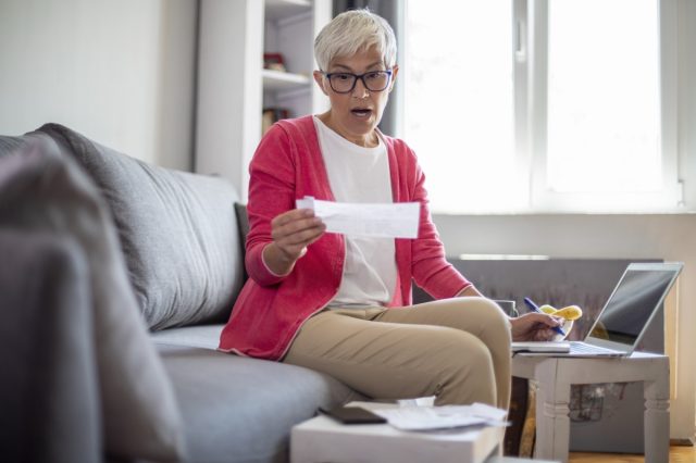 Une femme mature surprise compte les factures à la maison.