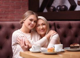 Mother and her adult daughter hugging in cafe