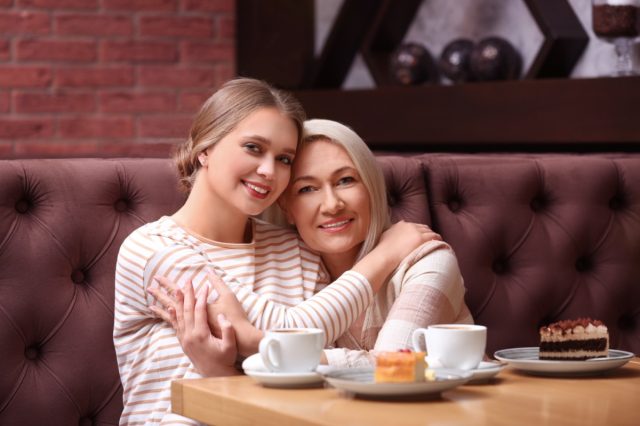 Mother and her adult daughter hugging in cafe