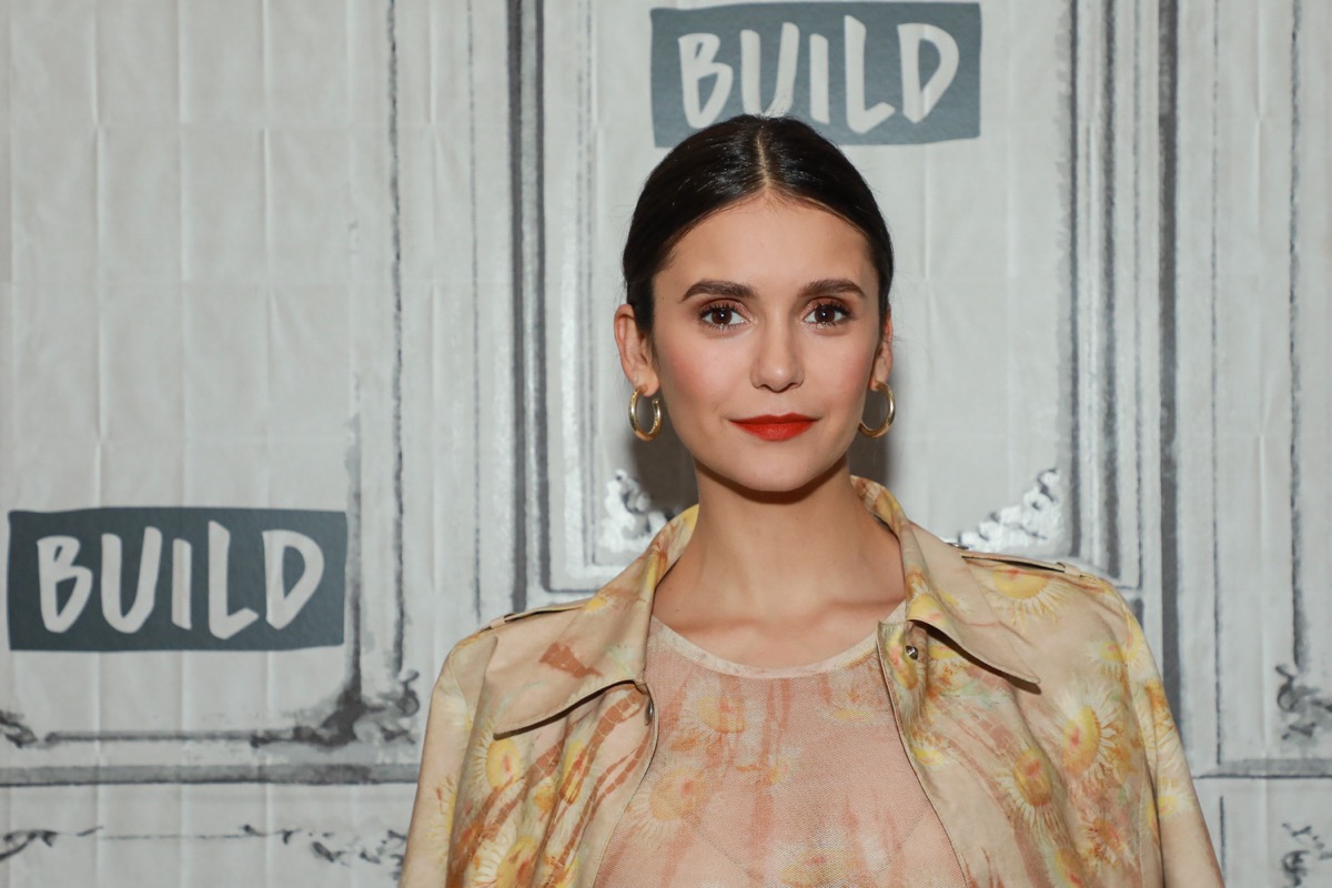 nina dobrev in tan floral outfit in front of build step-and-repeat