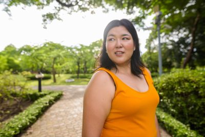 Overweight Asian woman wearing yellow orange dress relaxing in the park.