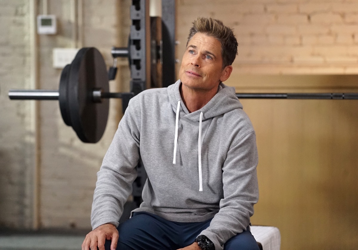 rob lowe sitting in front of weight bench