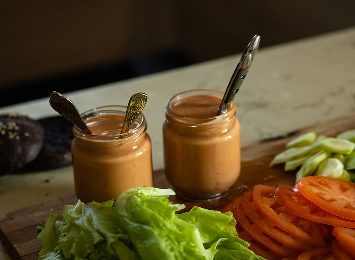 two jars of secret sauce with lettuce and sliced tomato