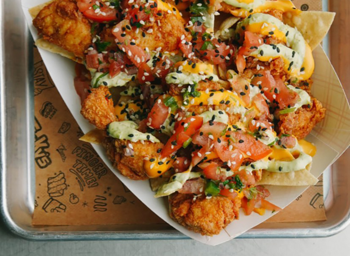 stickys chicken nachos topped with tomato and sesame seeds