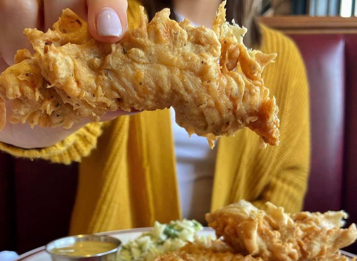 woman holding up a piece of fried chicken