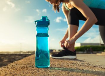 Drinking water concept. Female runner tying her shoe next to bottle of water.