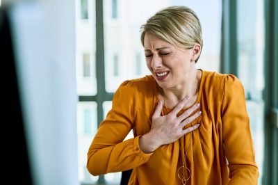 Businesswoman feeling chest pain while working in the office.