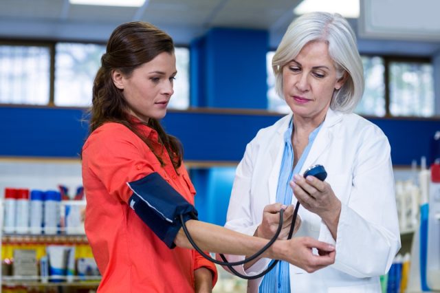 Pharmacist checking blood pressure of customer