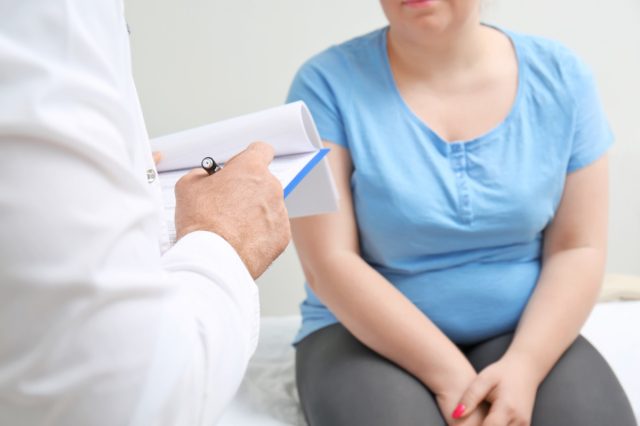Overweight woman discussing test results with doctor in hospital.