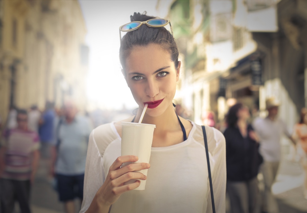 woman drinking out of white cup with straw