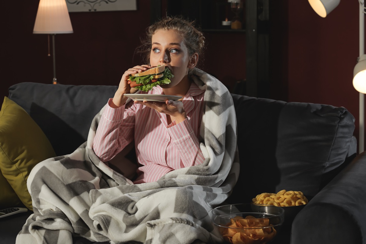 woman eating unhealthy food while watching TV at night.