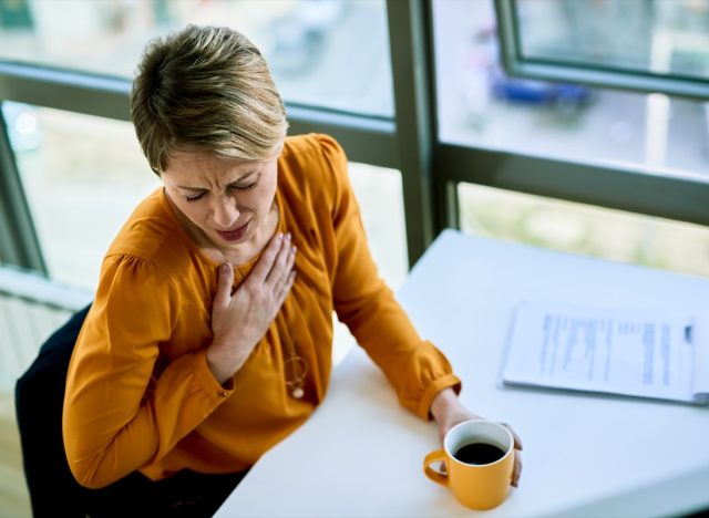Businesswoman coughing while having coffee break in the office.