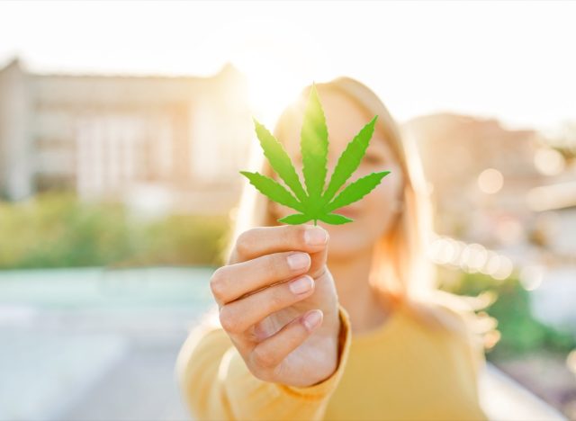 Young girl holding marijuana leaf with sunlight.
