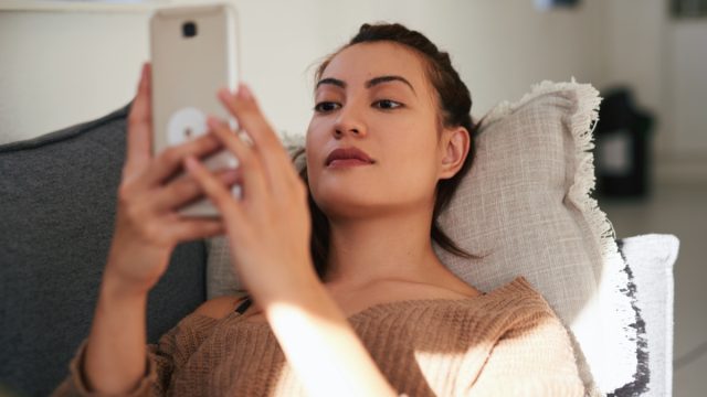 woman using a smartphone on the sofa at home