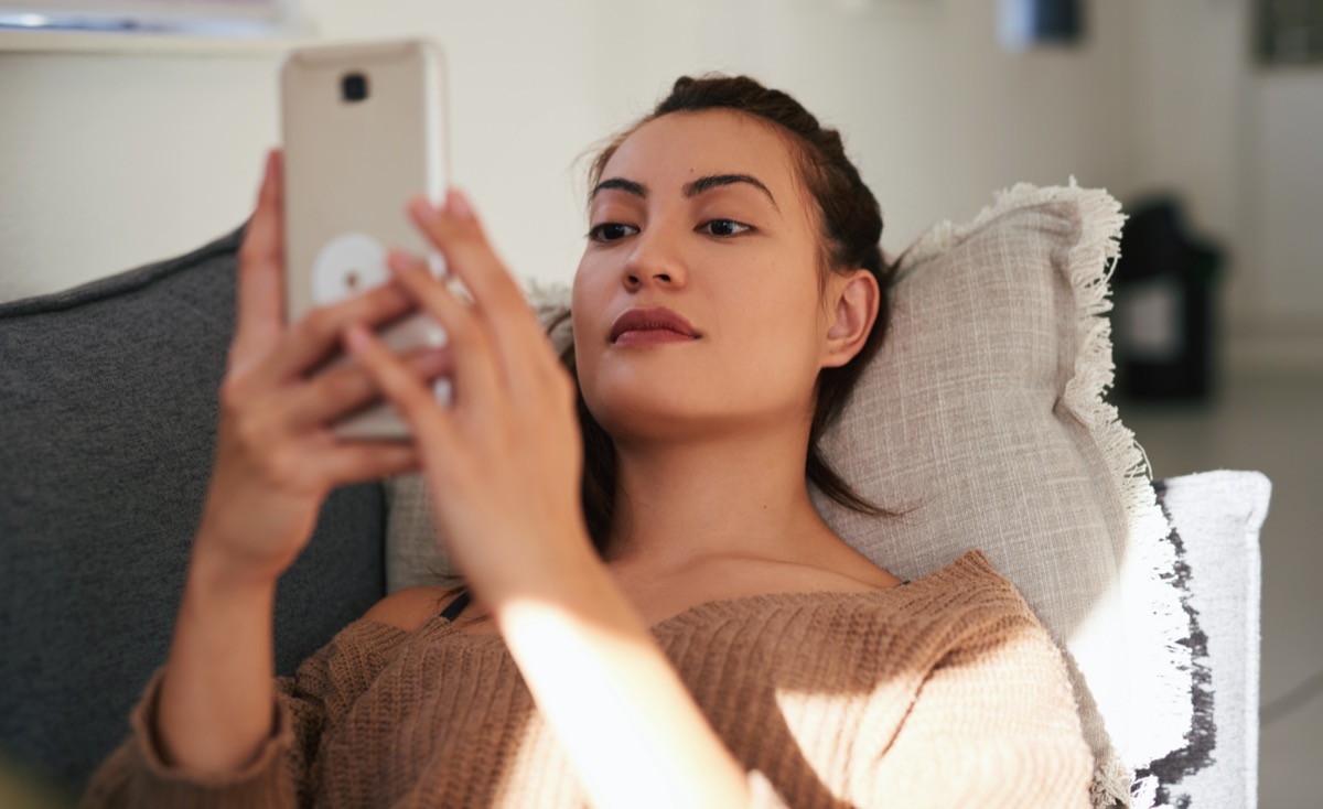 woman using a smartphone on the sofa at home