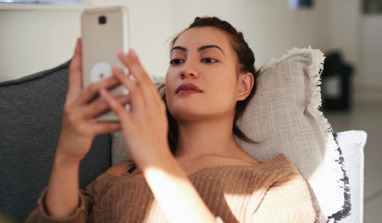woman using a smartphone on the sofa at home