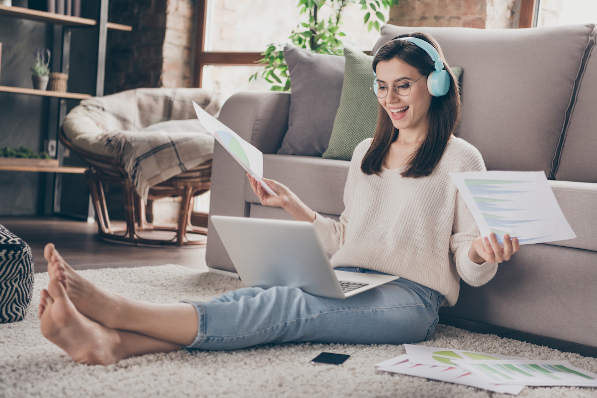 Full body photo of happy pretty girl hold paperwork look computer remote work sit floor inside home indoors