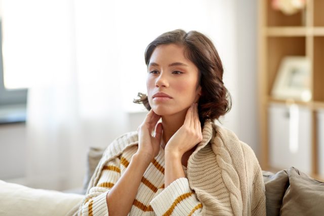 Sick woman touching her lymph nodes at home.