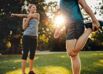 A man and a woman stretching in the park.
