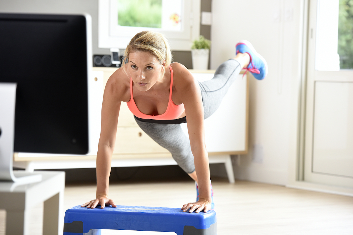 Fitness girl doing exercises in front of TV