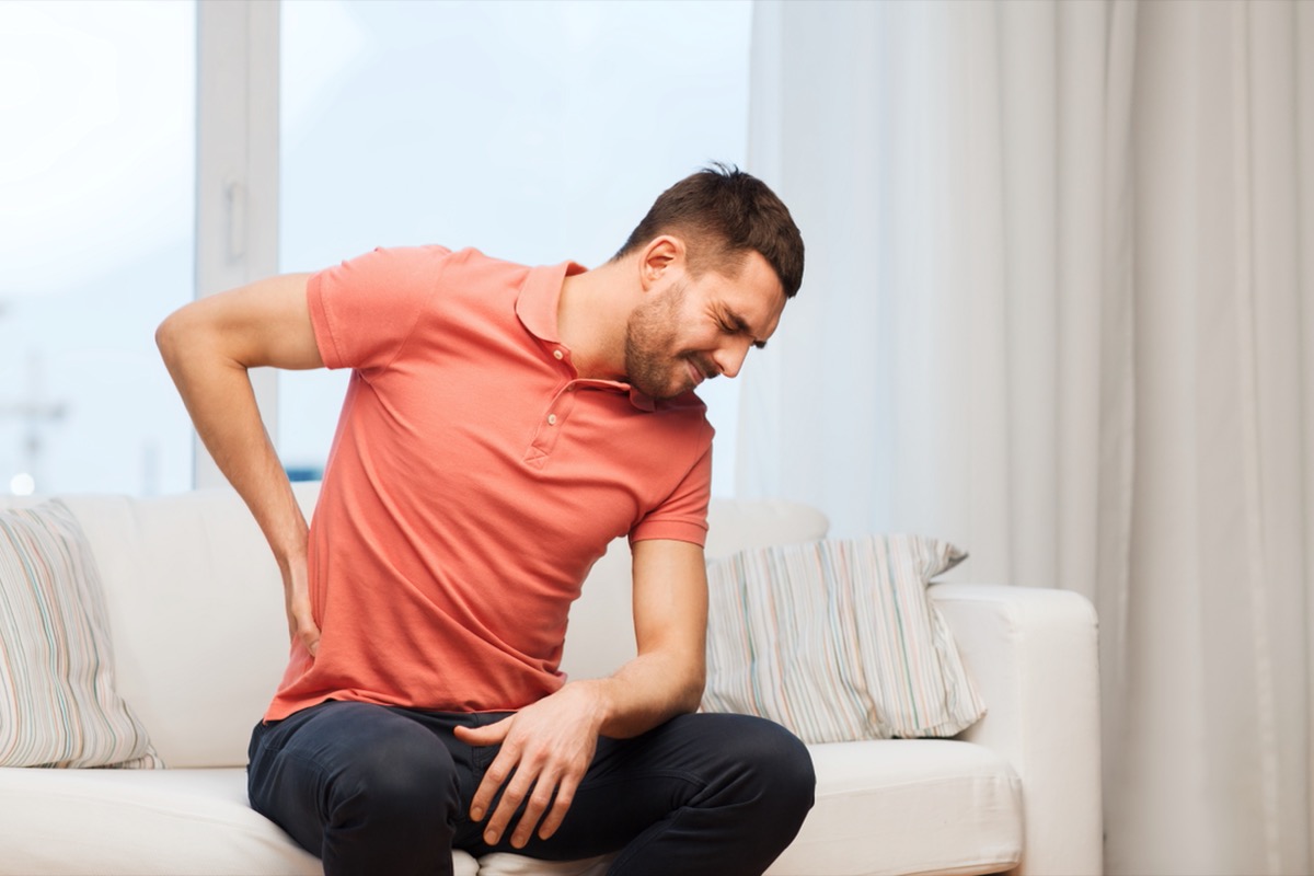 young man sitting on couch with kidney pain