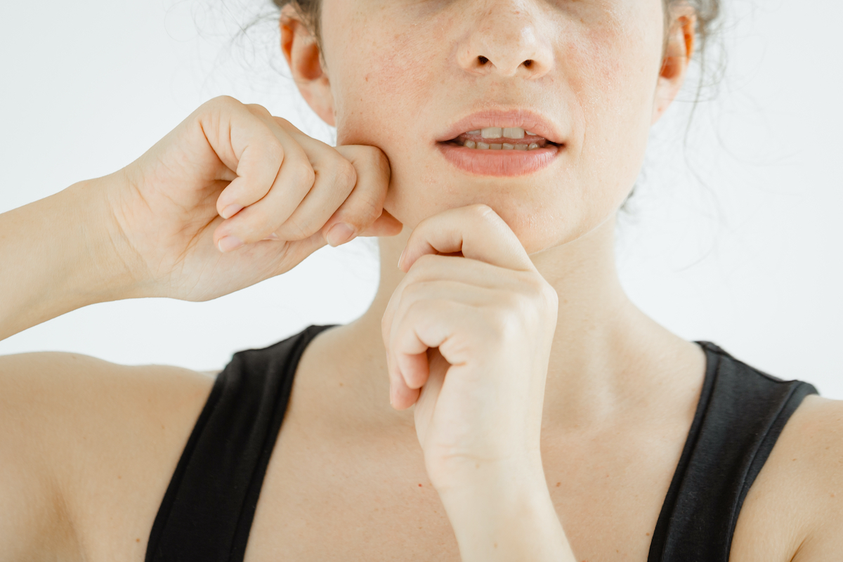 Caucasian young woman performing facial exercises - morning routine to strengthen the face contour. The concept of non-surgical rejuvenation and self-care. Closeup. Selective focus.