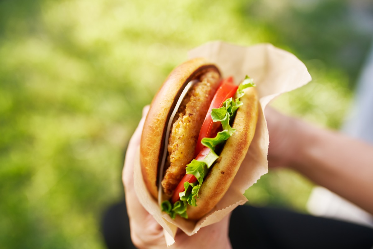 person eating fast food chicken sandwich