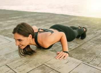 Young fit woman in sportswear doing push ups exercise on the beach