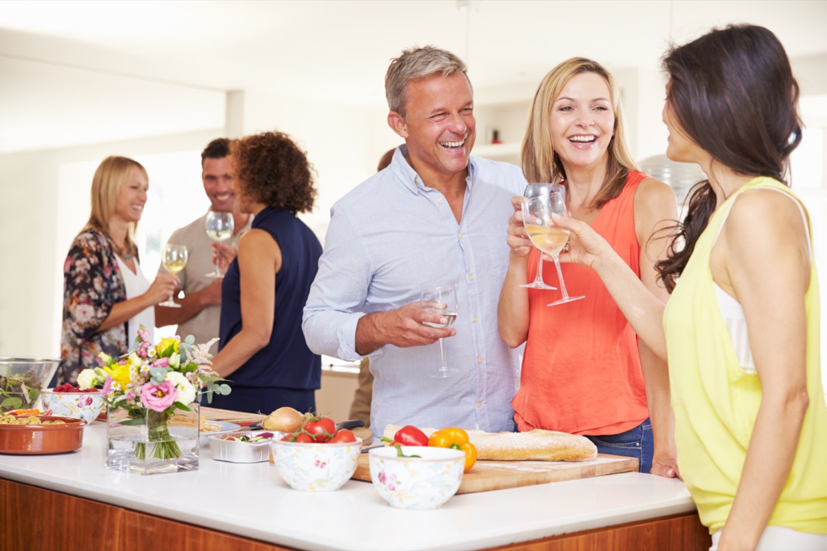 Mature Guests Being Welcomed At Dinner Party By Friends