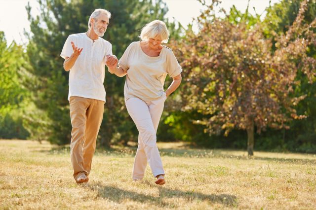 Mature couple holding hands on a walk in the park in summer