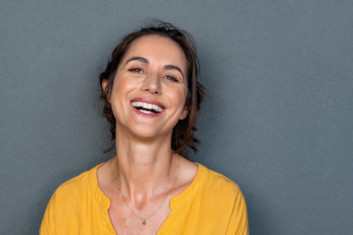 Middle aged woman in casual with toothy smile looking at camera