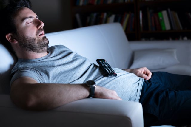 Lazy man watching tv at night alone