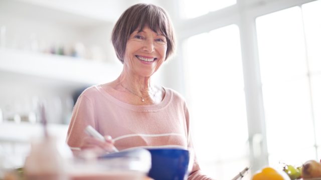Elderly woman in kitchen looking at camera smiling.