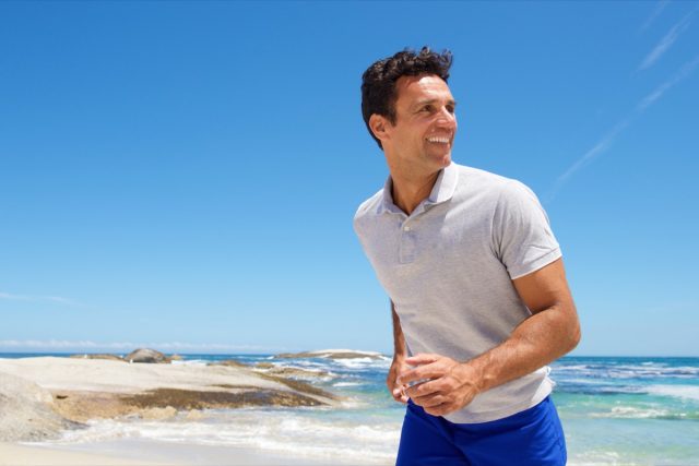 Portrait of a happy middle aged man walking on the beach