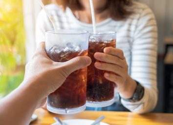 two people toasting with glasses of soda