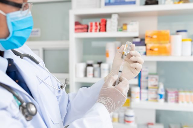 Hand of doctor holding syringe and vaccine