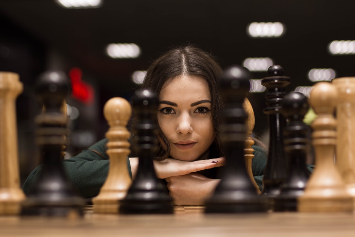 Woman looking at chess pieces.