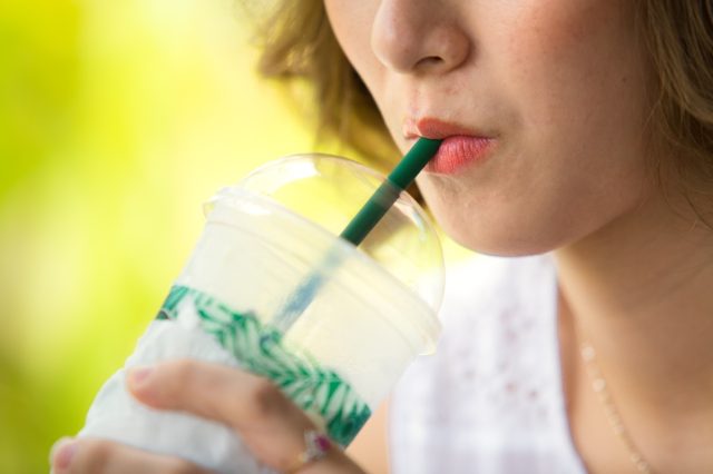 woman drinking iced coffee with a straw