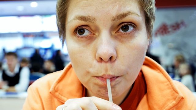 Woman drinks cola through drinking straw in fast food cafe restaurant.
