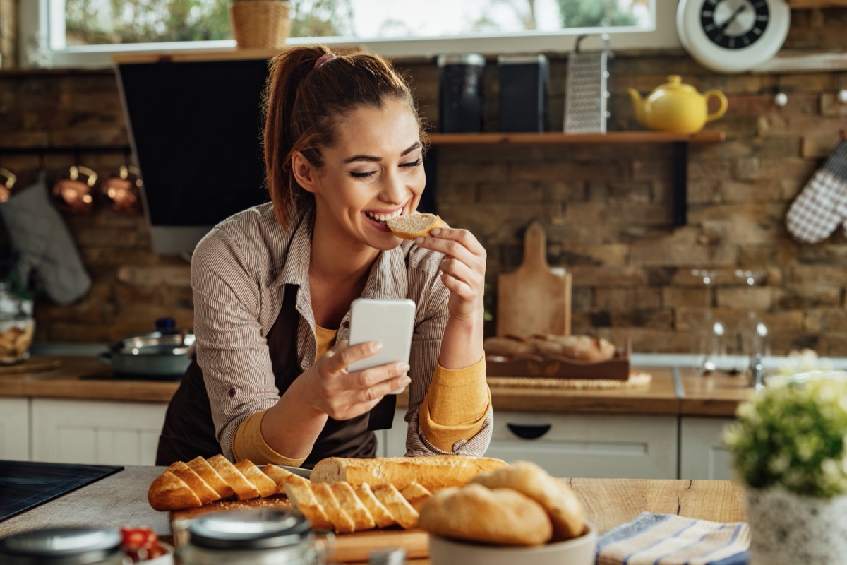 woman eating bread while text messaging