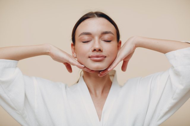 Young woman doing face building yoga facial gymnastics self massage and rejuvenating exercises