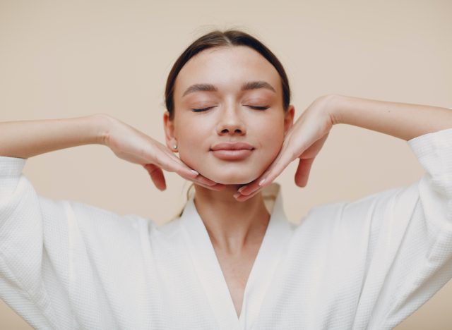 Young woman doing face building yoga facial gymnastics self massage and rejuvenating exercises