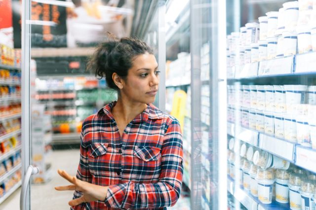Latin woman shopping in supermarket refrigerators