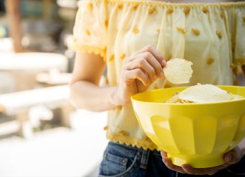 woman in yellow shirt holding yellow bowl of chips