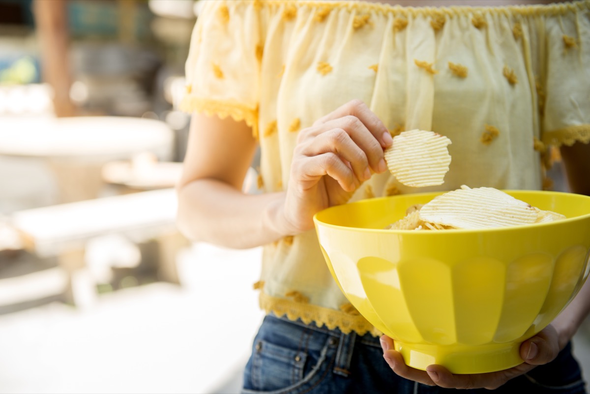 woman in yellow shirt holding yellow bowl of chips